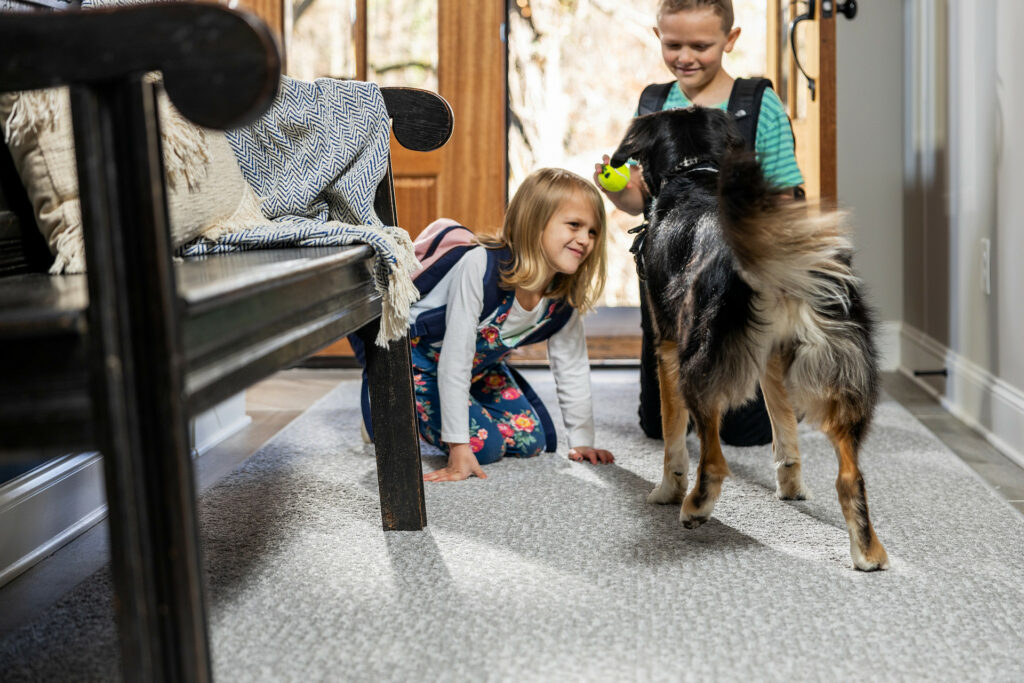 Kids plying with dog on carpet flooring | Pucher's Decorating Centers